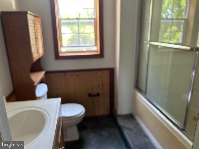 full bathroom featuring combined bath / shower with glass door, vanity, and toilet