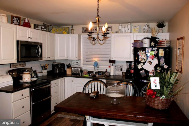 kitchen with black refrigerator, pendant lighting, white cabinetry, range with two ovens, and an inviting chandelier