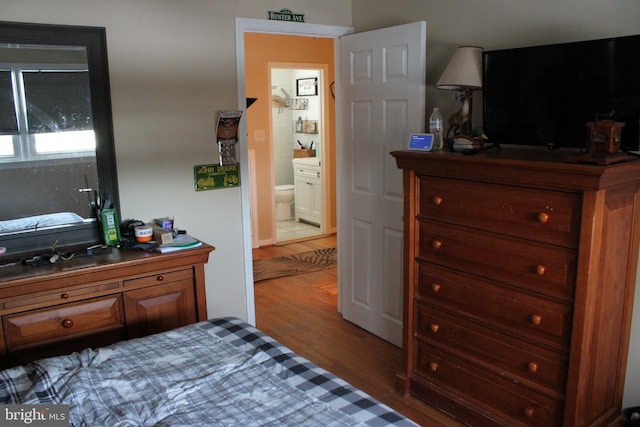 bedroom featuring ensuite bath and hardwood / wood-style floors