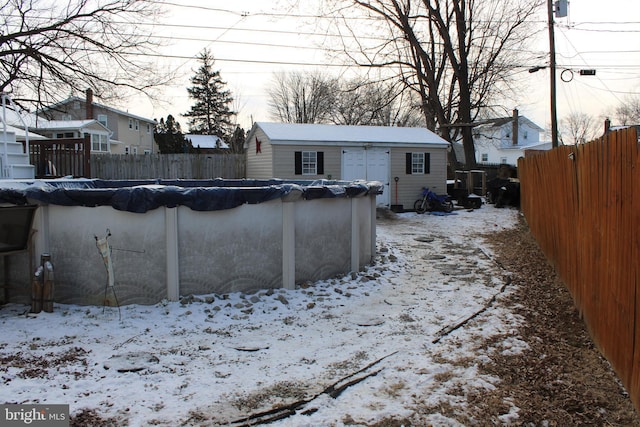 snowy yard with a covered pool and an outbuilding