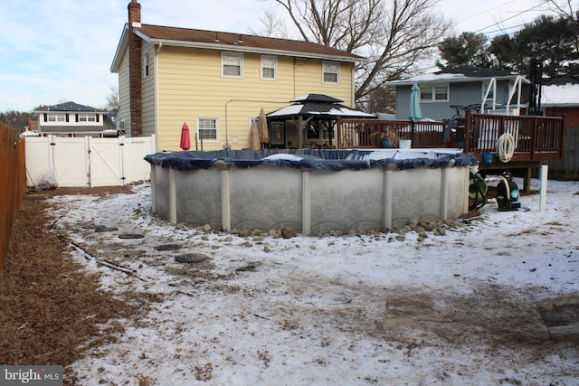 snow covered pool featuring a wooden deck and a gazebo