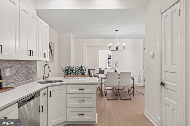 kitchen featuring stainless steel dishwasher, pendant lighting, light hardwood / wood-style flooring, a notable chandelier, and white cabinets