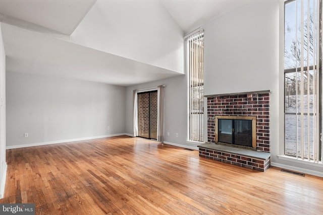 unfurnished living room featuring a fireplace, vaulted ceiling, and light hardwood / wood-style flooring