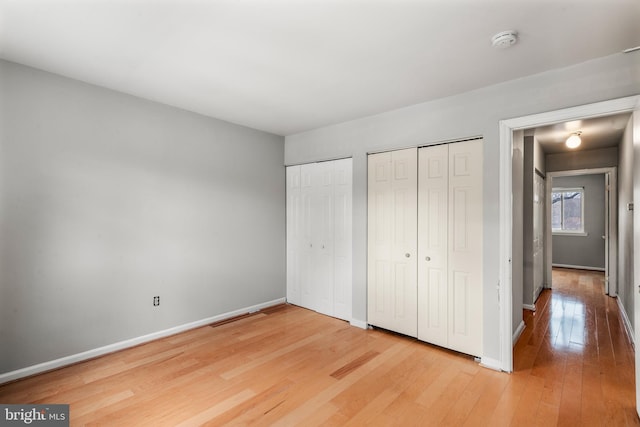 unfurnished bedroom with two closets and hardwood / wood-style flooring