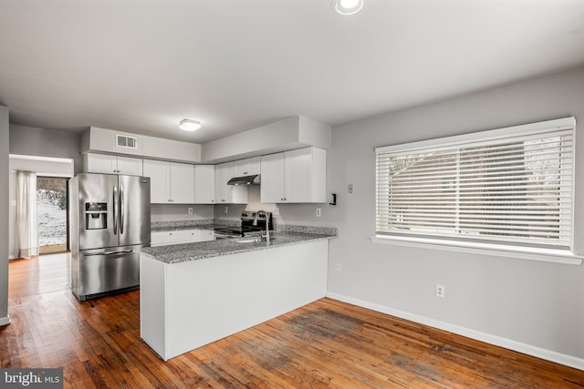 kitchen with white cabinets, appliances with stainless steel finishes, kitchen peninsula, and dark hardwood / wood-style floors