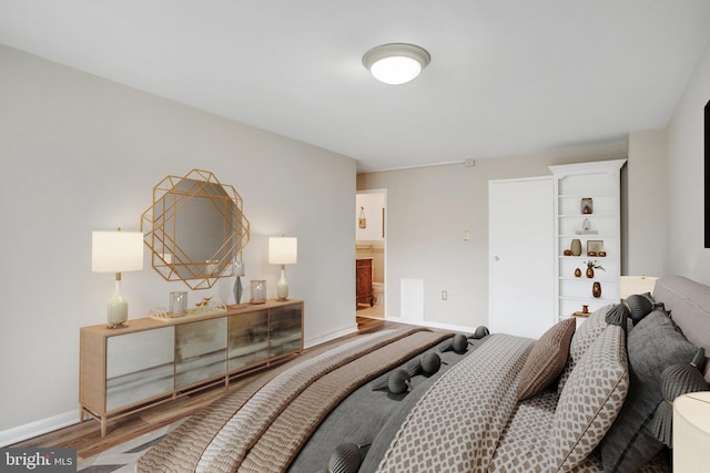 bedroom with wood-type flooring and connected bathroom