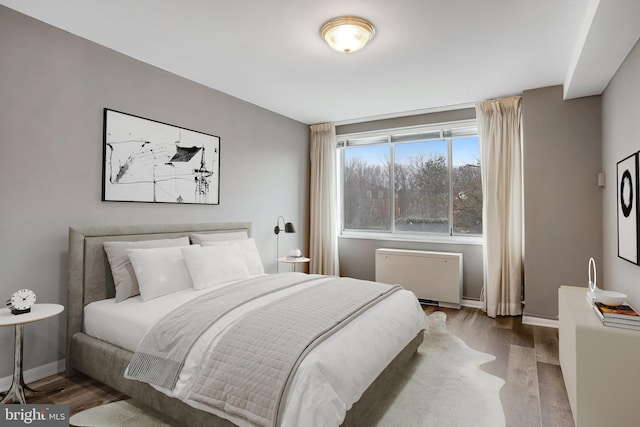 bedroom with radiator heating unit and hardwood / wood-style flooring