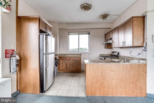 kitchen featuring appliances with stainless steel finishes, light stone counters, sink, and light tile patterned floors