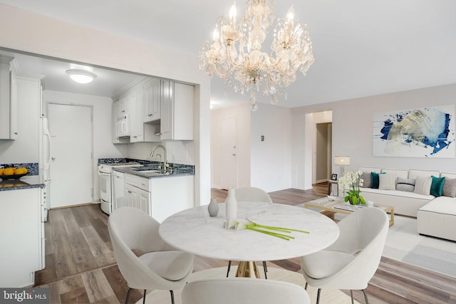 dining room featuring sink, hardwood / wood-style floors, and an inviting chandelier