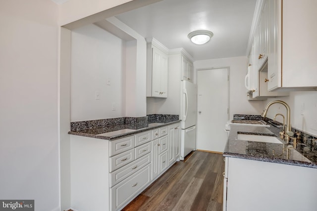 kitchen featuring white cabinets, white fridge, and dark stone counters