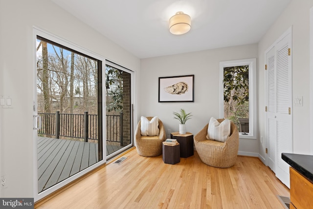 living area with wood finished floors, visible vents, and baseboards