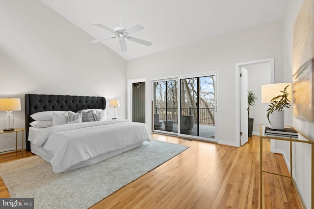 bedroom with light wood-type flooring, baseboards, high vaulted ceiling, and access to outside