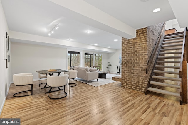 living area with recessed lighting, brick wall, stairs, and light wood finished floors