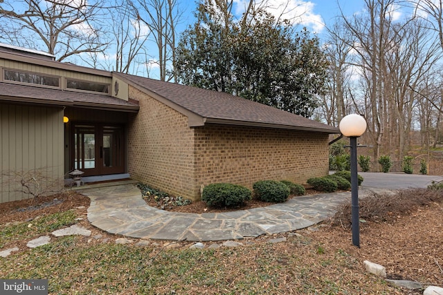 view of home's exterior with brick siding and a shingled roof