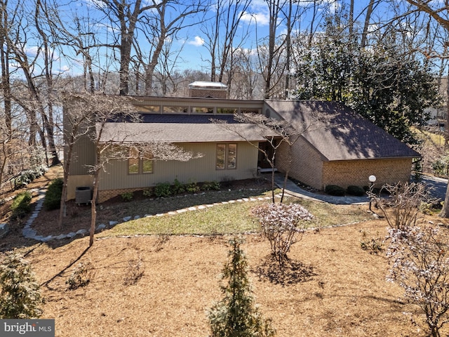 view of front of house with cooling unit, brick siding, and a shingled roof