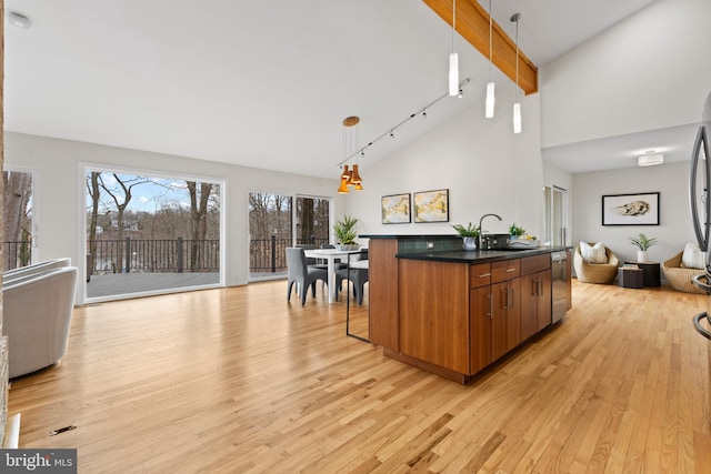 kitchen with dark countertops, open floor plan, brown cabinets, light wood-style floors, and a sink