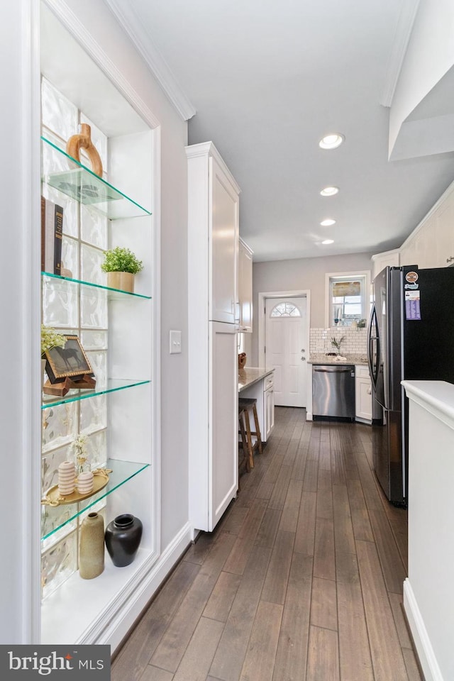 kitchen with stainless steel dishwasher, black refrigerator, dark hardwood / wood-style flooring, and white cabinetry