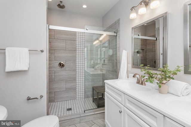 bathroom featuring toilet, an enclosed shower, and vanity