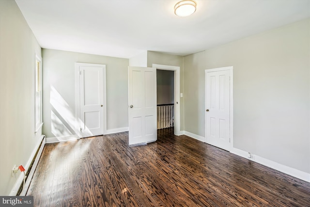 unfurnished bedroom with dark hardwood / wood-style flooring and a baseboard heating unit