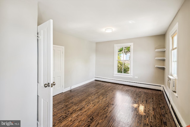 empty room with baseboard heating and dark hardwood / wood-style flooring