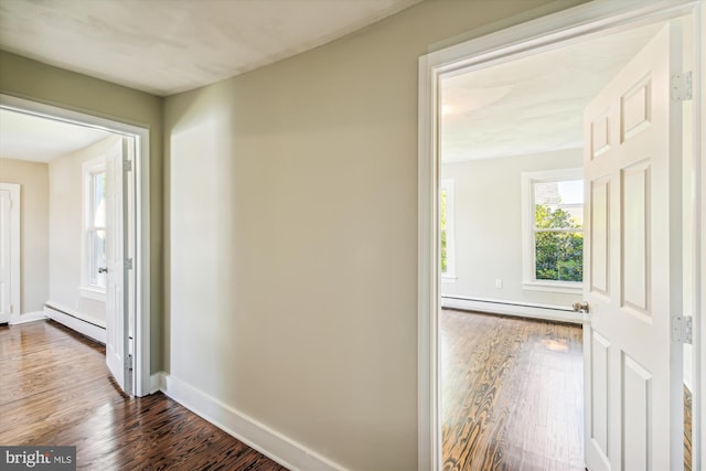 corridor with dark hardwood / wood-style floors and baseboard heating