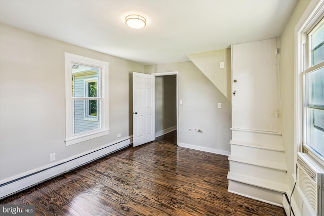 empty room featuring baseboard heating and dark wood-type flooring