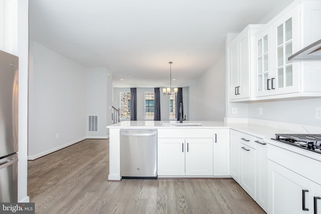 kitchen with white cabinetry, sink, stainless steel appliances, kitchen peninsula, and decorative light fixtures