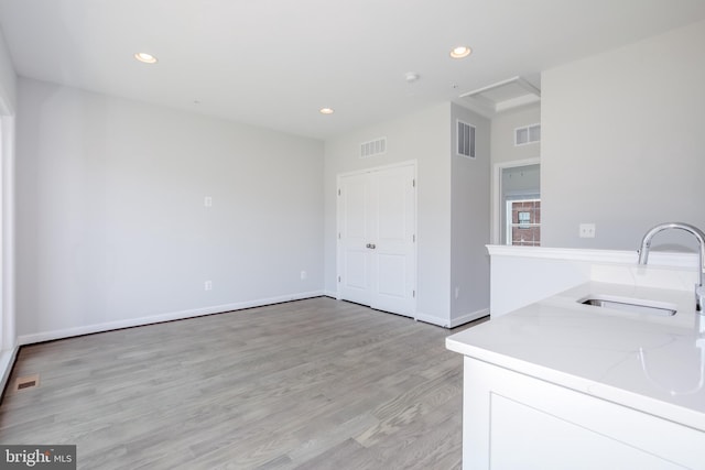 kitchen featuring light stone countertops, sink, and light hardwood / wood-style flooring