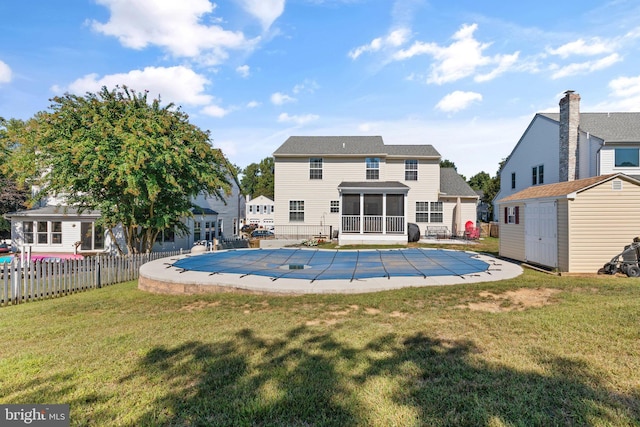 view of swimming pool with a patio, a yard, a sunroom, and a storage shed