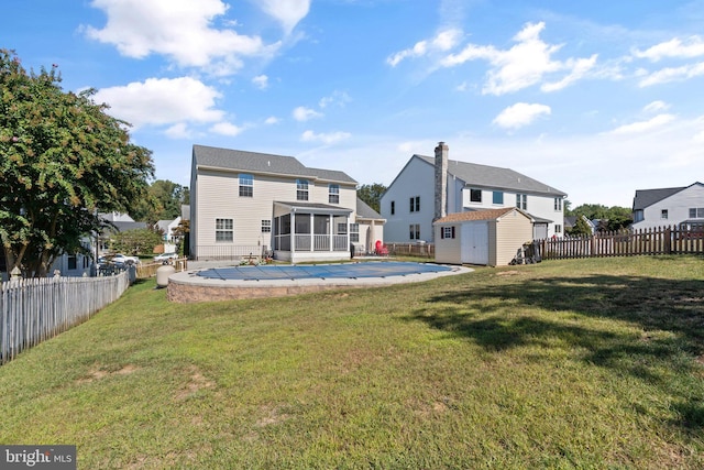 back of property with a patio, a covered pool, a sunroom, a lawn, and a shed