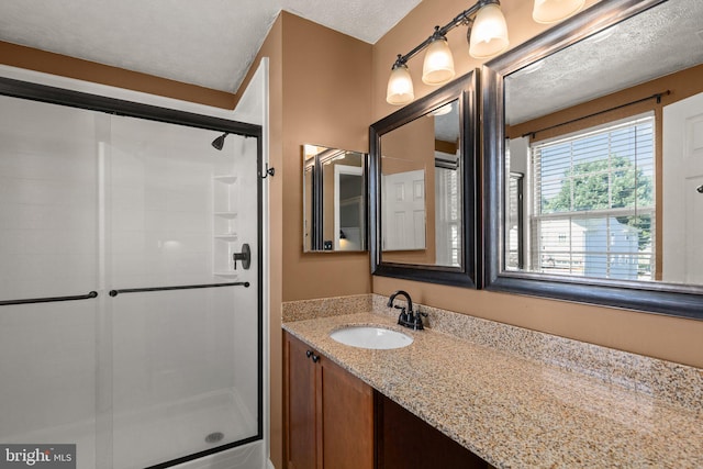 bathroom featuring a shower with door, vanity, and a textured ceiling