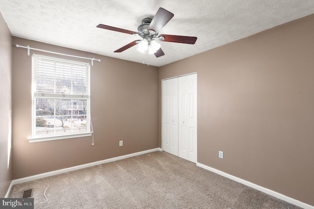 unfurnished bedroom with ceiling fan, a closet, carpet floors, and a textured ceiling