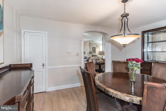 dining area with light hardwood / wood-style floors and a textured ceiling