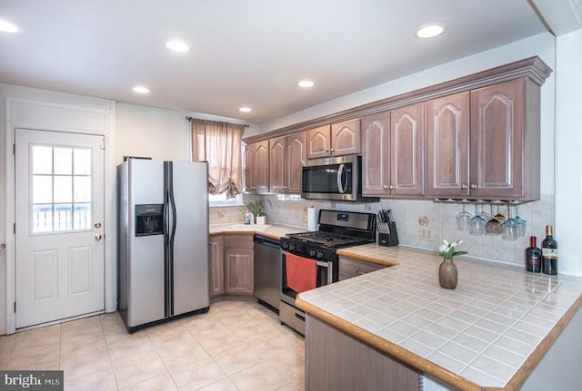 kitchen featuring stainless steel appliances, a wealth of natural light, tile countertops, and kitchen peninsula