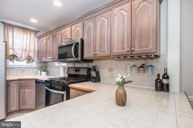 kitchen featuring stainless steel appliances, tile counters, and backsplash