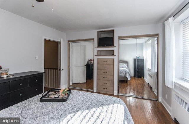 bedroom featuring radiator, two closets, and dark hardwood / wood-style floors