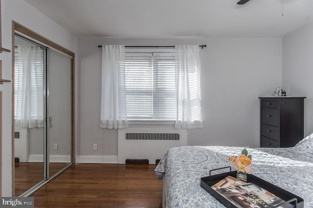 bedroom featuring dark wood-type flooring, radiator heating unit, and a closet