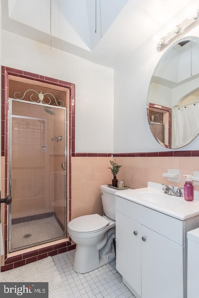 bathroom with tile walls, tile patterned flooring, vanity, tiled shower, and toilet