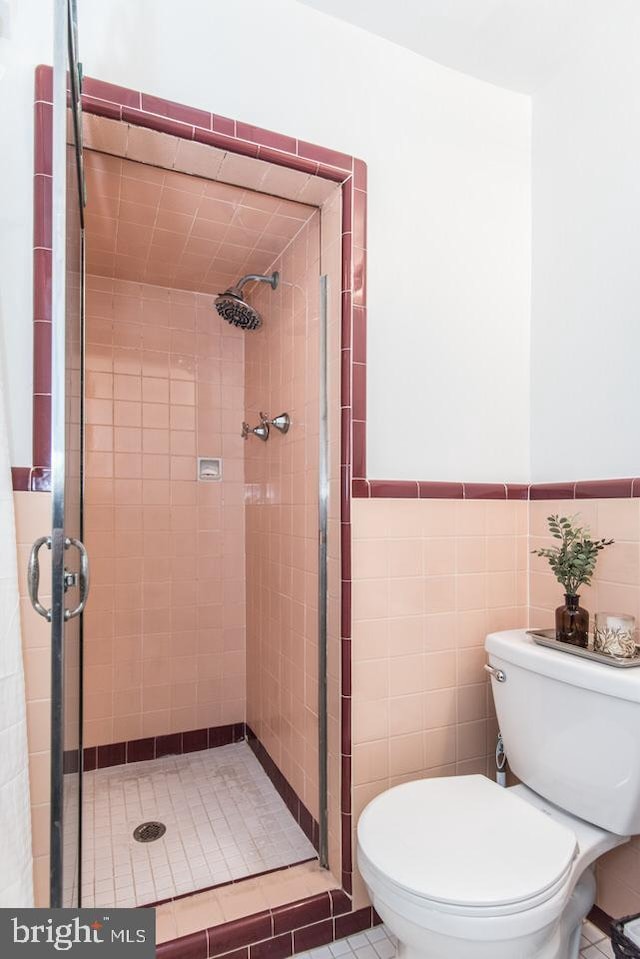 bathroom with toilet, tile walls, and a tile shower