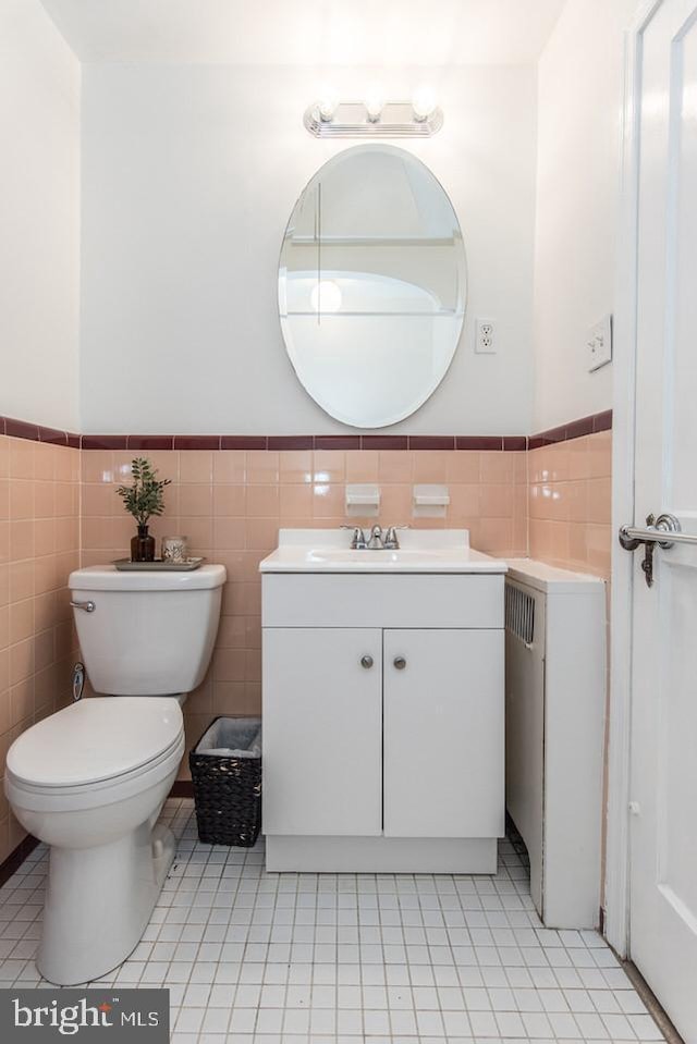 bathroom with tile patterned floors, vanity, toilet, and tile walls