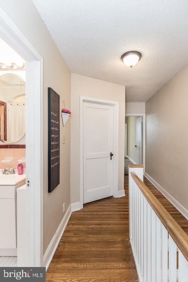 hall featuring dark hardwood / wood-style flooring, sink, and a textured ceiling