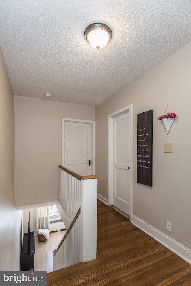 corridor featuring dark hardwood / wood-style flooring and a textured ceiling