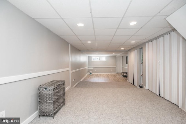 basement with light colored carpet and a drop ceiling