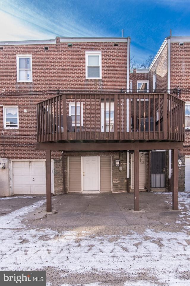 snow covered back of property with a garage