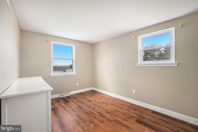 spare room with a healthy amount of sunlight and dark hardwood / wood-style floors