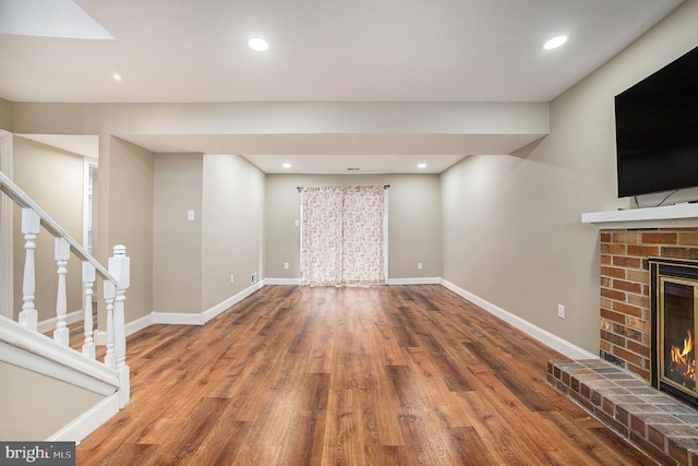 unfurnished living room featuring a brick fireplace and wood-type flooring