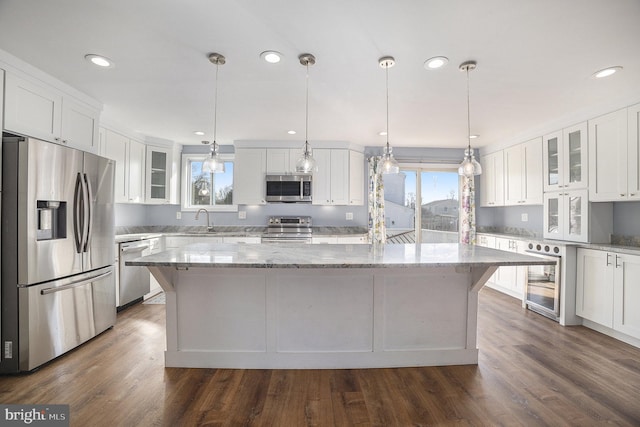 kitchen with white cabinetry, hanging light fixtures, a spacious island, and appliances with stainless steel finishes