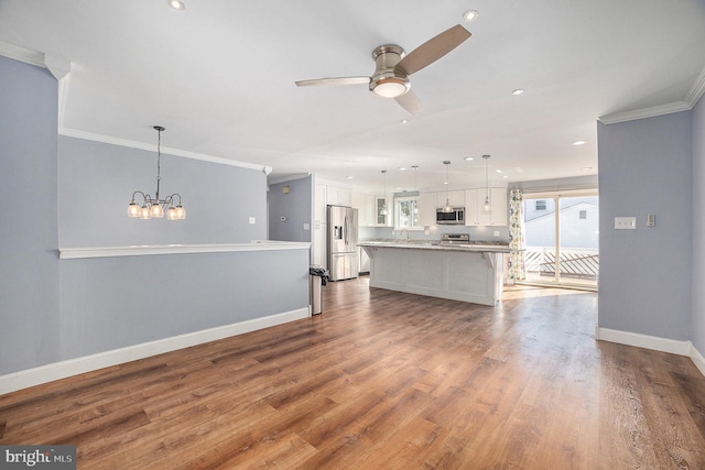 unfurnished living room with crown molding, wood-type flooring, and ceiling fan with notable chandelier