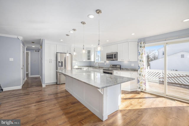 kitchen featuring pendant lighting, white cabinets, a center island, light stone counters, and stainless steel appliances