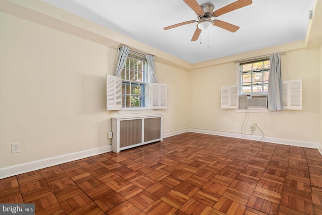 empty room with dark parquet flooring, radiator, a healthy amount of sunlight, and ceiling fan